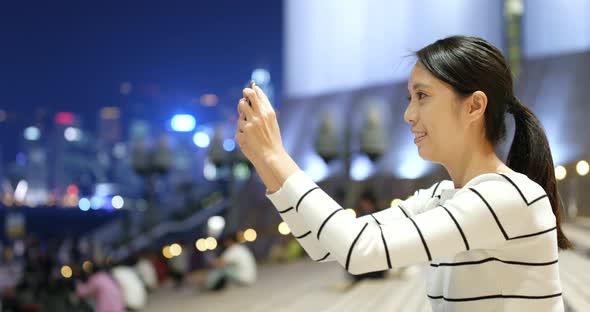 Woman taking video by cellphone in city