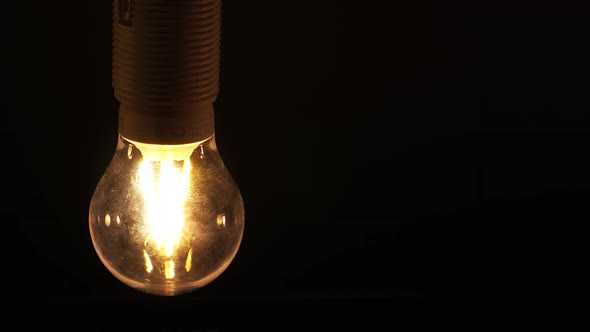 The Lamp Turns on and Off Close Up with Yellow Light on a Black  Background.