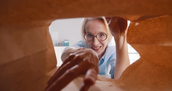 View From Inside Paper Bag of Mature Businesswoman Taking Croissant and Eating