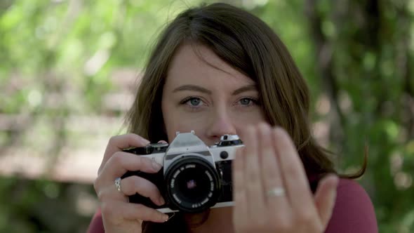 Woman photographer looking through viewfinder and asking you to move forward