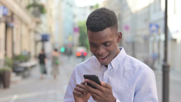 African Man Celebrating on Smartphone While Standing Outdoor