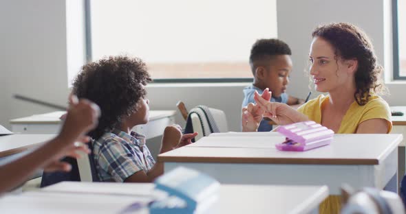 Video of happy caucasian female teacher learning math to african american boy alt