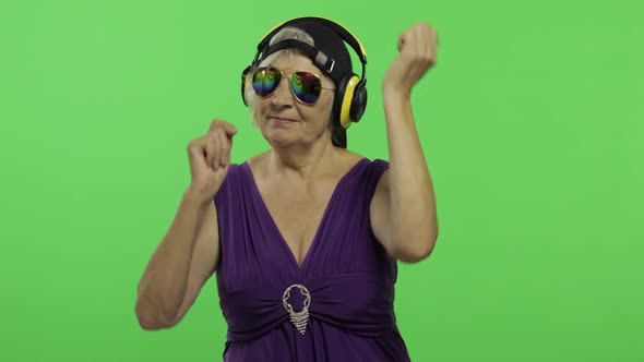 Elderly Woman Listens To Music in Headphones and Dances. Grandmother. Chroma Key