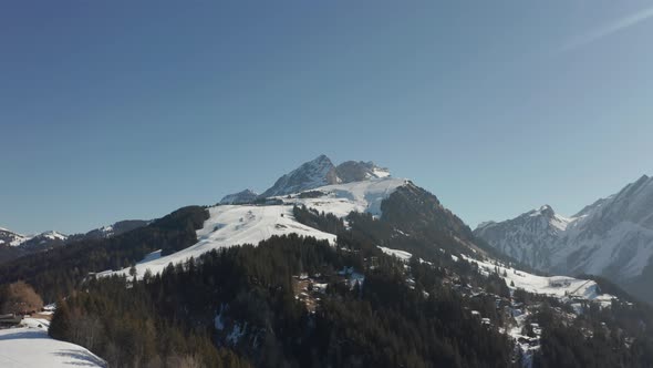 Aerial of beautiful snow covered mountainscape with distant cabins and town