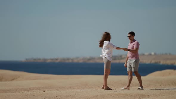 Young Loving Man and Woman are Walking on Cliff with Sea View Hugging and Holding Hands