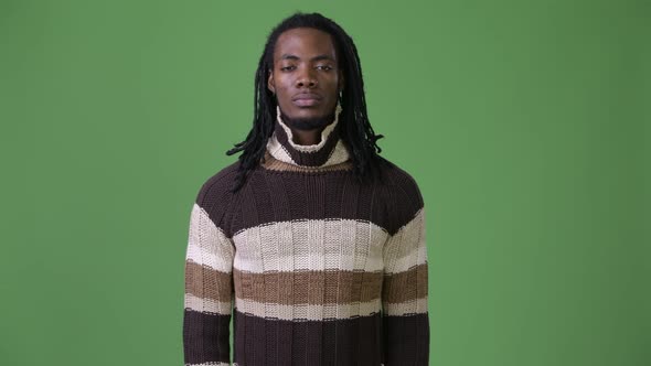 Young Handsome African Man with Dreadlocks Against Green Background