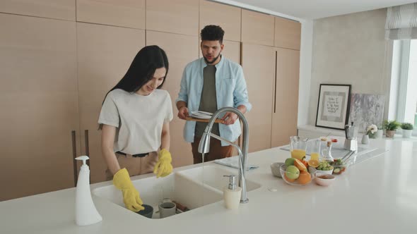 Man Helping Wife To Wash Dishes After Breakfast