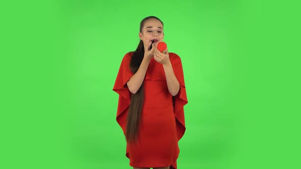 Pretty Young Woman Is Painting Her Lips Looking in Red Mirror. Green Screen