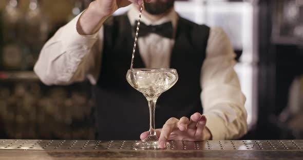Close-up Shooting. Bartender Is Turning the Ice in Glass Using the Bar Spoon