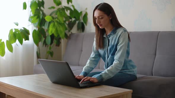 Long Haired Lady Sits at Wooden Table with Black Laptop