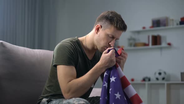 US Male Soldier Sitting on Sofa and Kissing National Flag, Patriotism and Pride