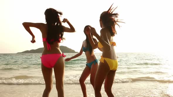 Group of women in bikini having fun dancing on the beach