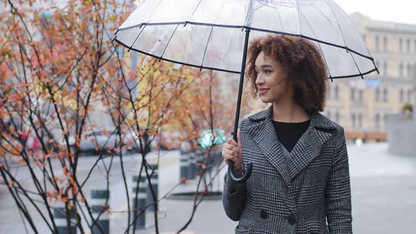 Young Beautiful African American Woman Curly Girl Female Tourist in Stylish Coat Stands in City in