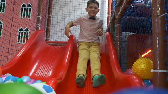 Boy in Shirt with Bow Tie Slides Into Pool with Balls