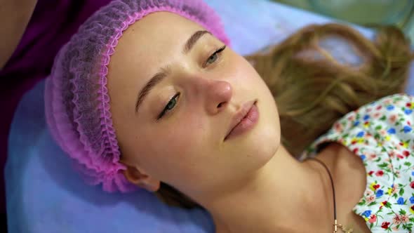 Professional beautician conducts face procedures on girl`s face. 