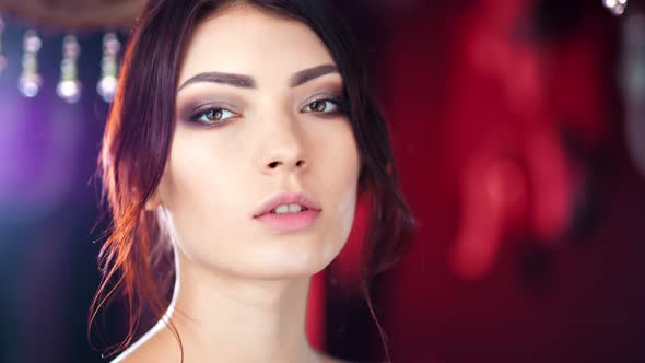 Closeup Face of Charming Sensual Young Caucasian Woman Posing at Red Lights Background