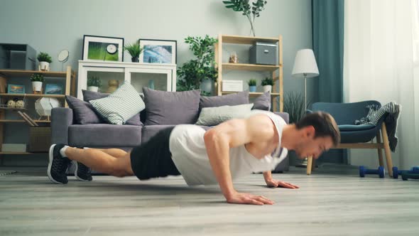 Young Handsome Man Clapping Hands While Doing Advanced Pushups at Home on Floor