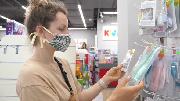 Coronavirus Pandemic! Young Woman in Protective Mask Chooses Baby Products in the Store.