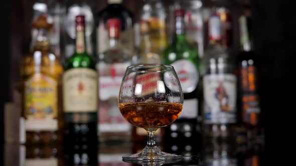 Closeup of a Bartender Pouring Cognac Into a Glass for a Businessman in a Bar