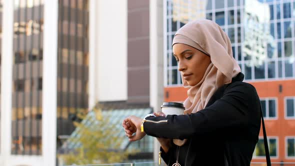 Side view of young Asian woman in hijab standing in the city 4k