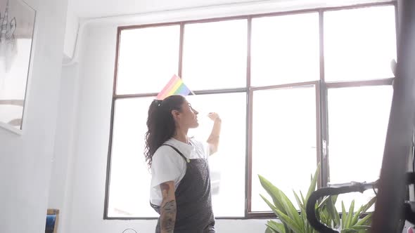 Young Lesbian Woman Dances Joyfully at Home with LGTBQ Flag