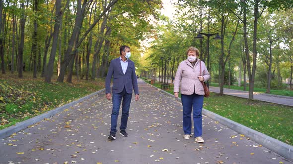 Middle Aged Couple in Masks Walking in Autumn Park