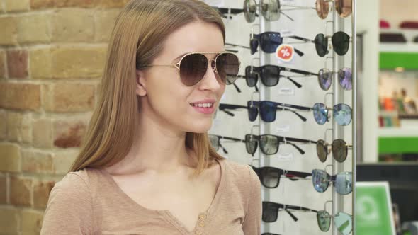 Cheerful Beautiful Woman Trying Sunglasses at Optometrist Store