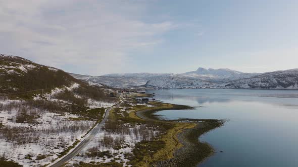 Scenic road along Daafjord through snowy landscape, Ringvassoya; aerial