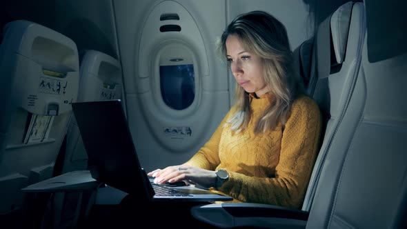 Female Freelancer Working on Laptop Sitting In Airplane. A Lady Is Working on a Laptop in Semi