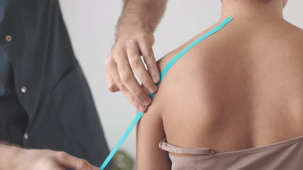 Physiotherapist Applying Kinesio Tape on Patient Shoulder