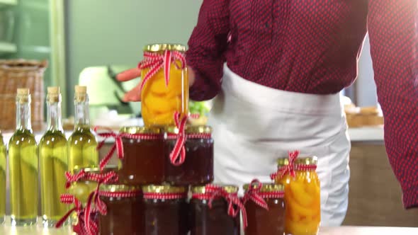 Female staff showing jars of preserves and olive oil on counter