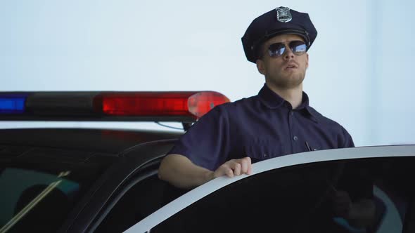 Officer Getting Out From Car and Informing Station About Crime on Two-Way Radio