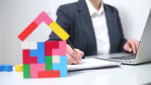 A real estate agent works on a computer and draws up documents for the sale of a house.