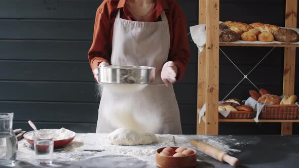 Female Baker Sifting Flour while Preparing Dough