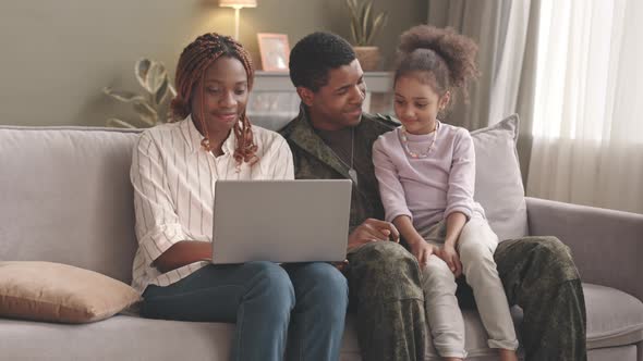 Military Family of Three Using Laptop Together at Home alt