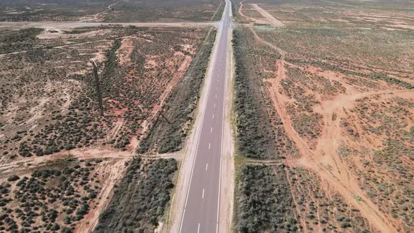 Drone aerial over country desert road in Australia pan up to reveal wind farm renewable energy