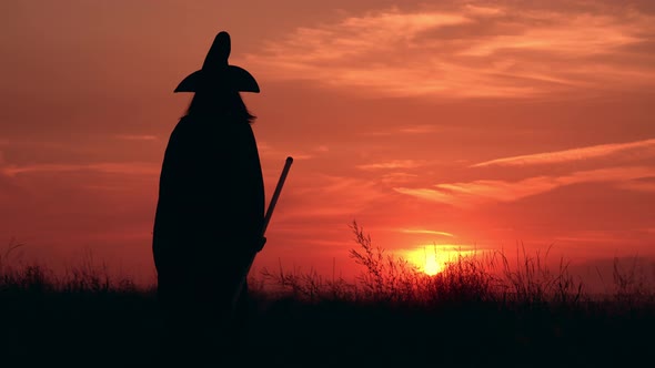 Witch Holds a Broom Goes From the Camera View on the Field