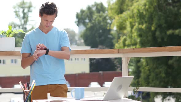 Sunny Day, Man Standing and Using Smartwatch in Balcony, Gadget