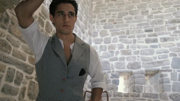 Attractive young fashion man in a suit posing in an old fortress. Slow motion
