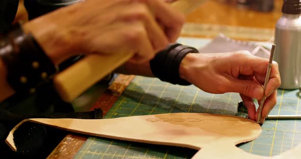 Close-up of craftswoman nailing leather