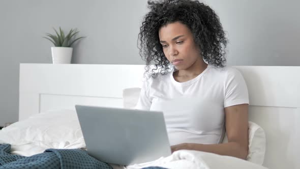 African Woman Working on Laptop in Bed