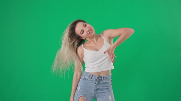 Beautiful Young Girl with Long Hair Actively Dances and Turns Her Head on a Green Background
