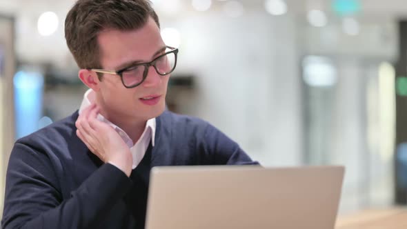 Young Businessman with Laptop Having Neck Pain