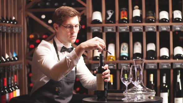 Waiter Opening Red Wine Bottle with Corkscrew in Restaurant