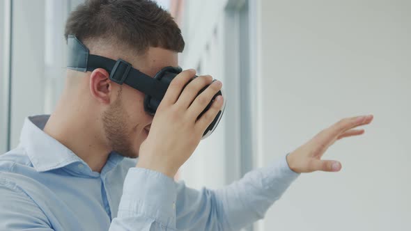 Close Up Young Man Sitting at a Desk in the Office Uses Augmented Reality Glasses To Work