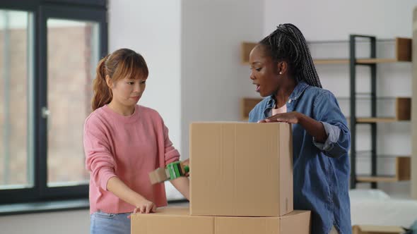 Women with Adhesive Tape Packing Boxes at Home