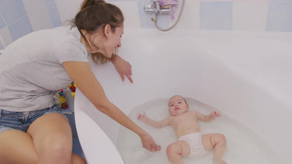 Mother Bathing Little Baby In Bathtub