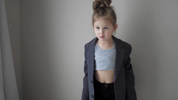 Rocker Girl Child in Big Jacket Dances Against the Background of the Wall of the House and Enjoys