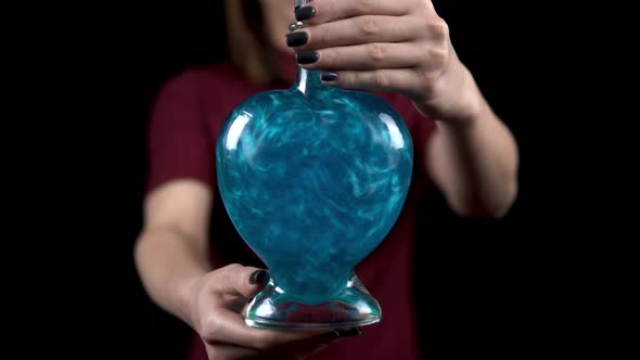 A Young Woman Holds Out a Bottle with a Love Potion in the Camera. Glass Bottle in the Form