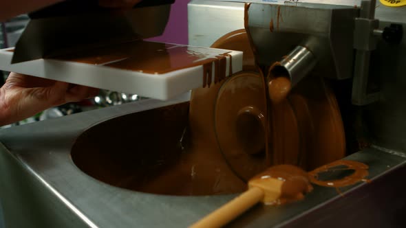 Worker filling mould with melted chocolate